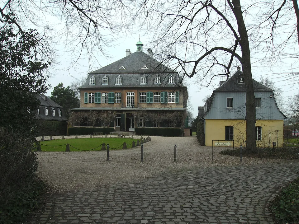 Schloss Eicherhof in Leichlingen hinter einem von Bäumen gesäumten Vorplatz