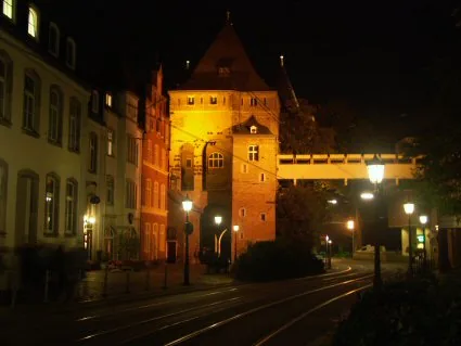 Beleuchtetes Obertor in Neuss mit angrenzenden Häusern am Abend